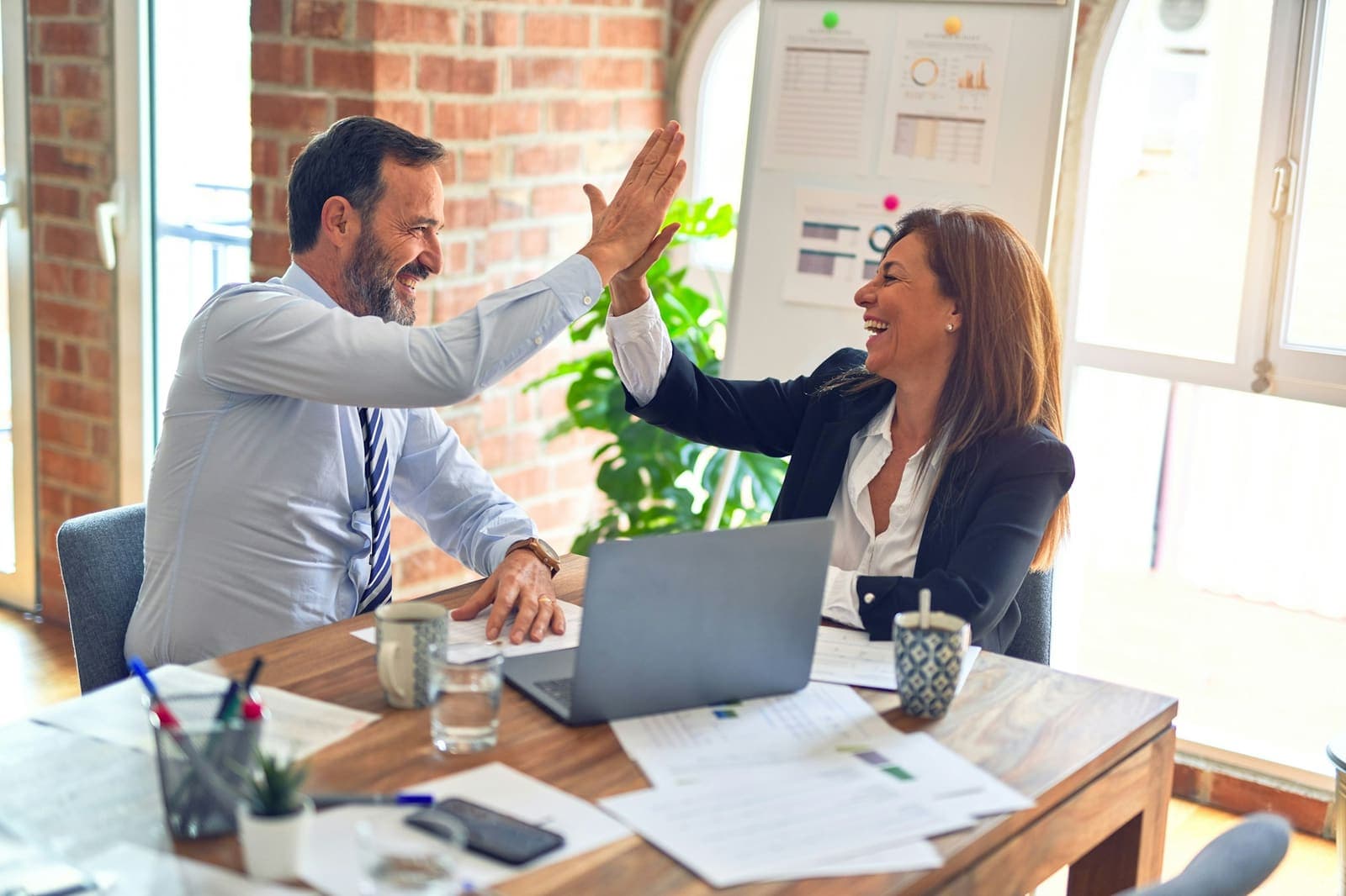 Two colleagues high-fiving across a desk